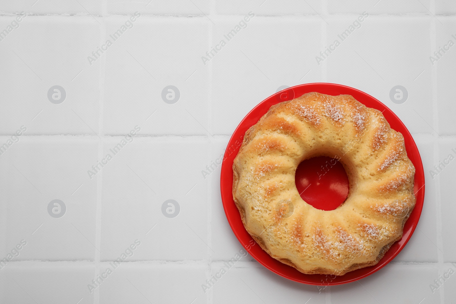 Photo of Delicious freshly baked sponge cake on white tiled table, top view. Space for text