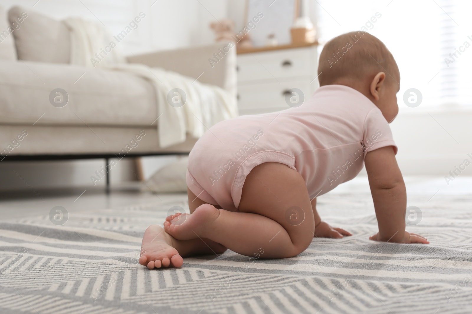 Photo of Cute baby crawling at home, focus on legs