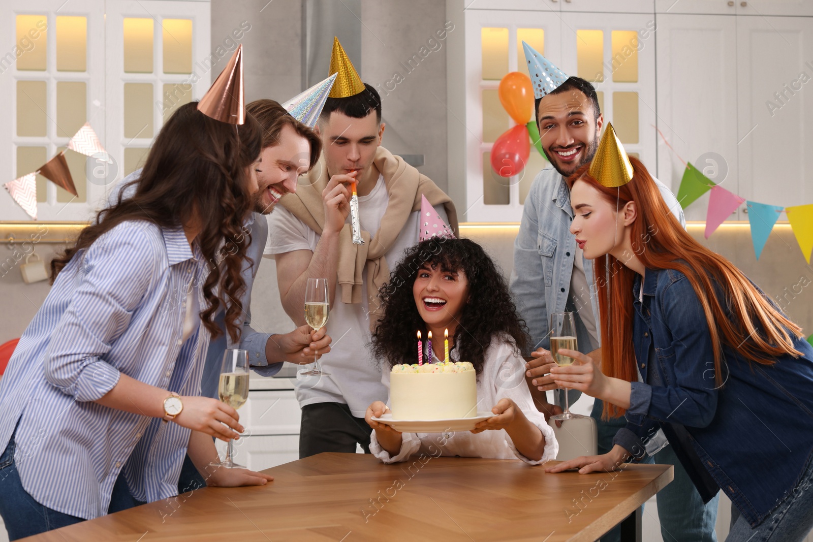 Photo of Happy friends with tasty cake celebrating birthday in kitchen