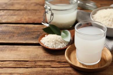 Photo of Glass of rice water on wooden table. Space for text