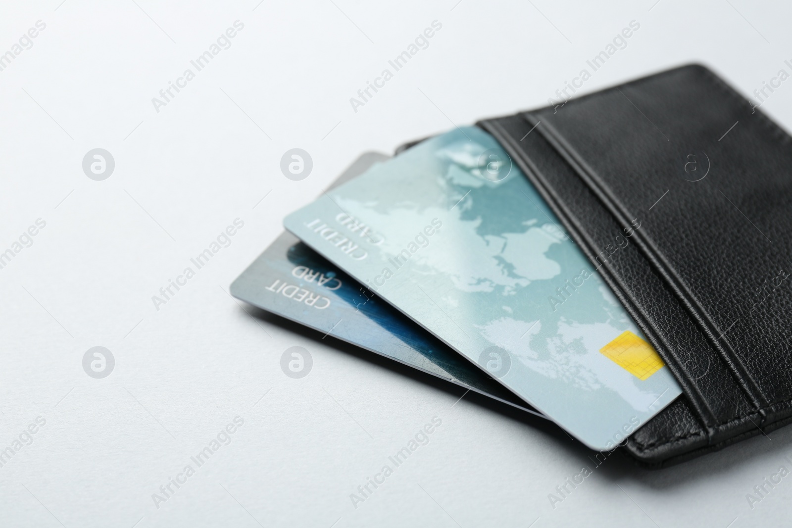 Photo of Woman holding leather card holder with credit cards on light grey background, closeup