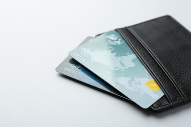 Woman holding leather card holder with credit cards on light grey background, closeup