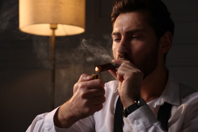 Photo of Handsome man lightning cigar at home. Space for text