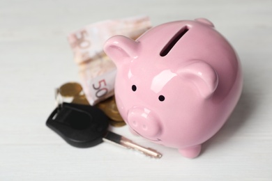 Photo of Piggy bank with key and money on light table