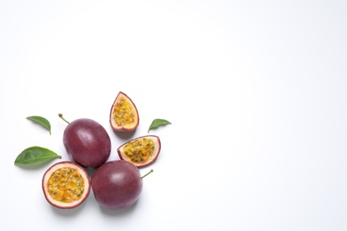 Photo of Fresh ripe passion fruits (maracuyas) with leaves on white background, flat lay. Space for text