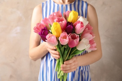 Photo of Girl holding bouquet of beautiful spring tulips on color background, closeup. International Women's Day