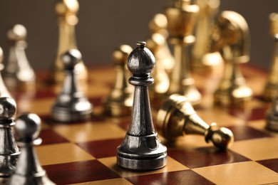 Chessboard with game pieces on grey background, closeup