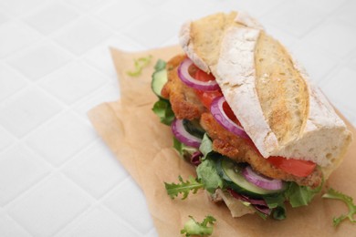 Photo of Delicious sandwich with schnitzel on white tiled table, closeup. Space for text