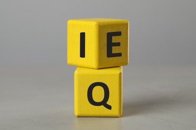Photo of Yellow cubes with letters E, I and Q on light grey stone table