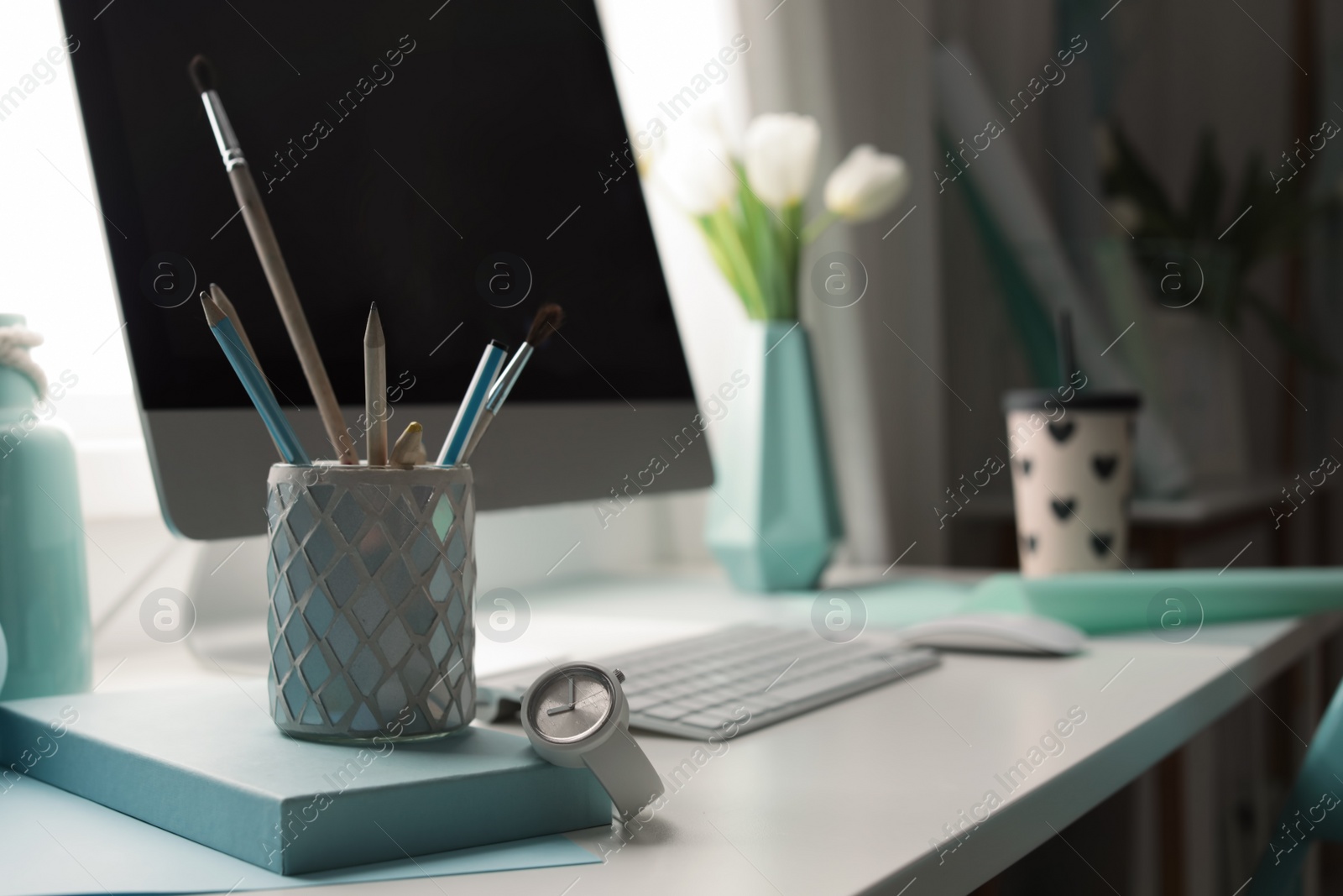 Photo of Stylish workplace with modern computer on desk. Focus on pencil holder and watch