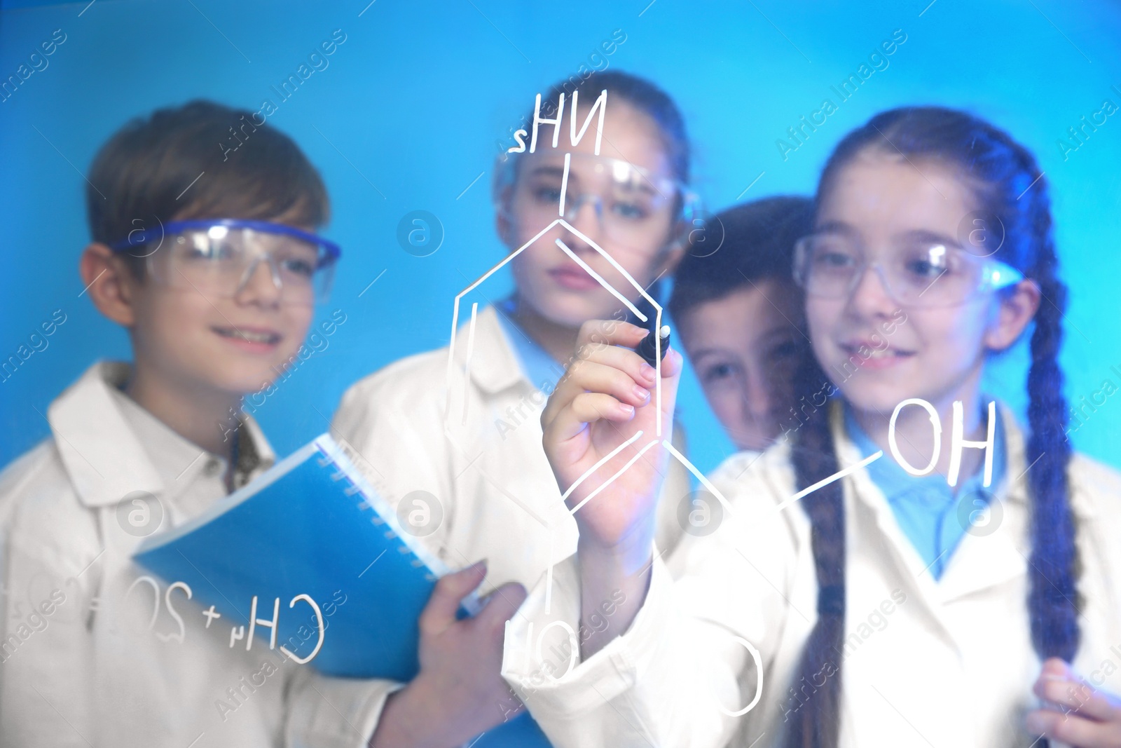 Photo of Pupils writing chemistry formula on glass board against color background