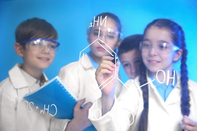 Photo of Pupils writing chemistry formula on glass board against color background