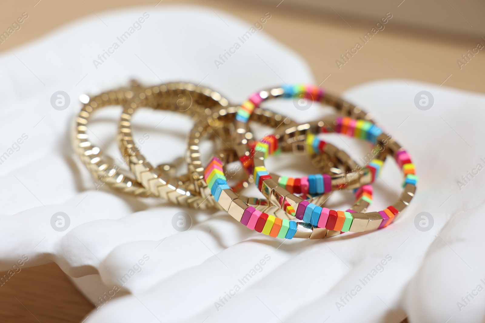 Photo of Ceramic hand stand with many different bracelets on table, closeup