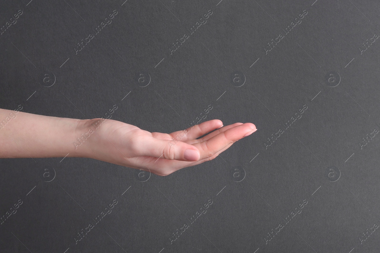 Photo of Woman holding hand on black background, closeup