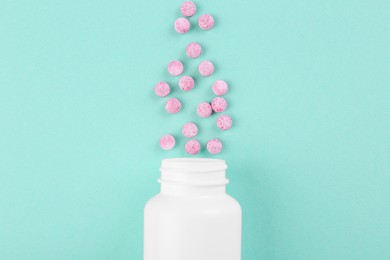 Bottle and vitamin pills on turquoise background, top view