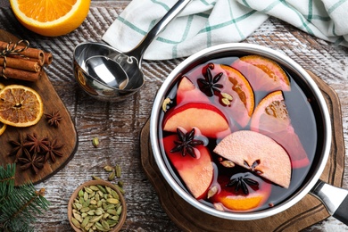 Delicious mulled wine and ingredients on wooden table, flat lay