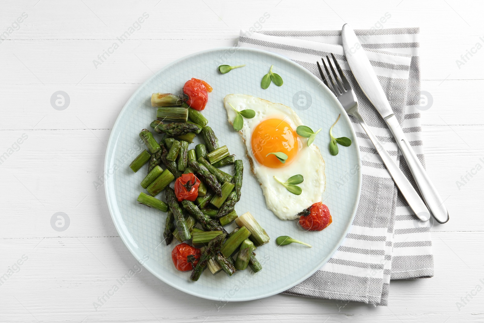 Photo of Oven baked asparagus served with fried egg on white wooden table, flat lay