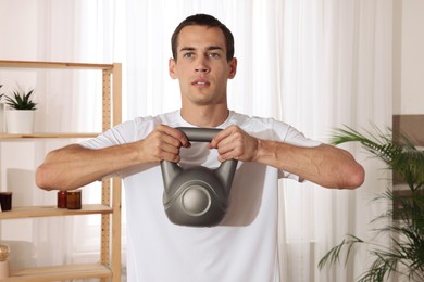 Handsome man training with kettlebell at home