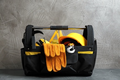 Photo of Black bag with construction tools on table