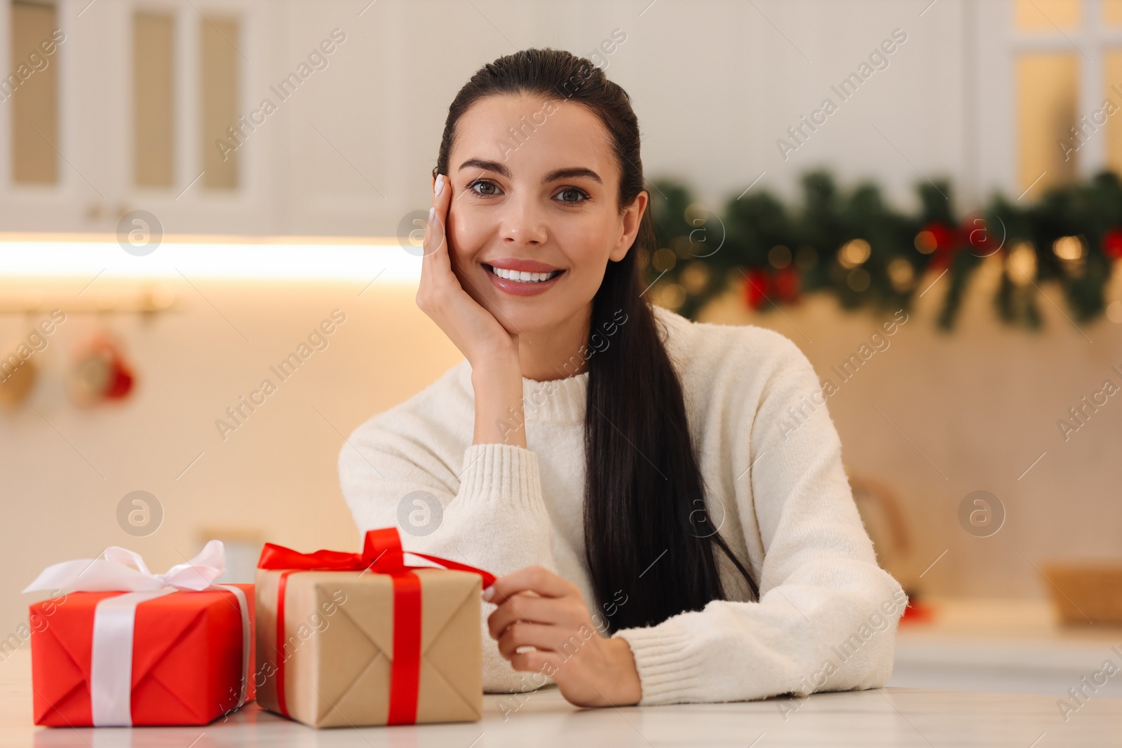 Photo of Portrait of smiling woman with Christmas gifts at home