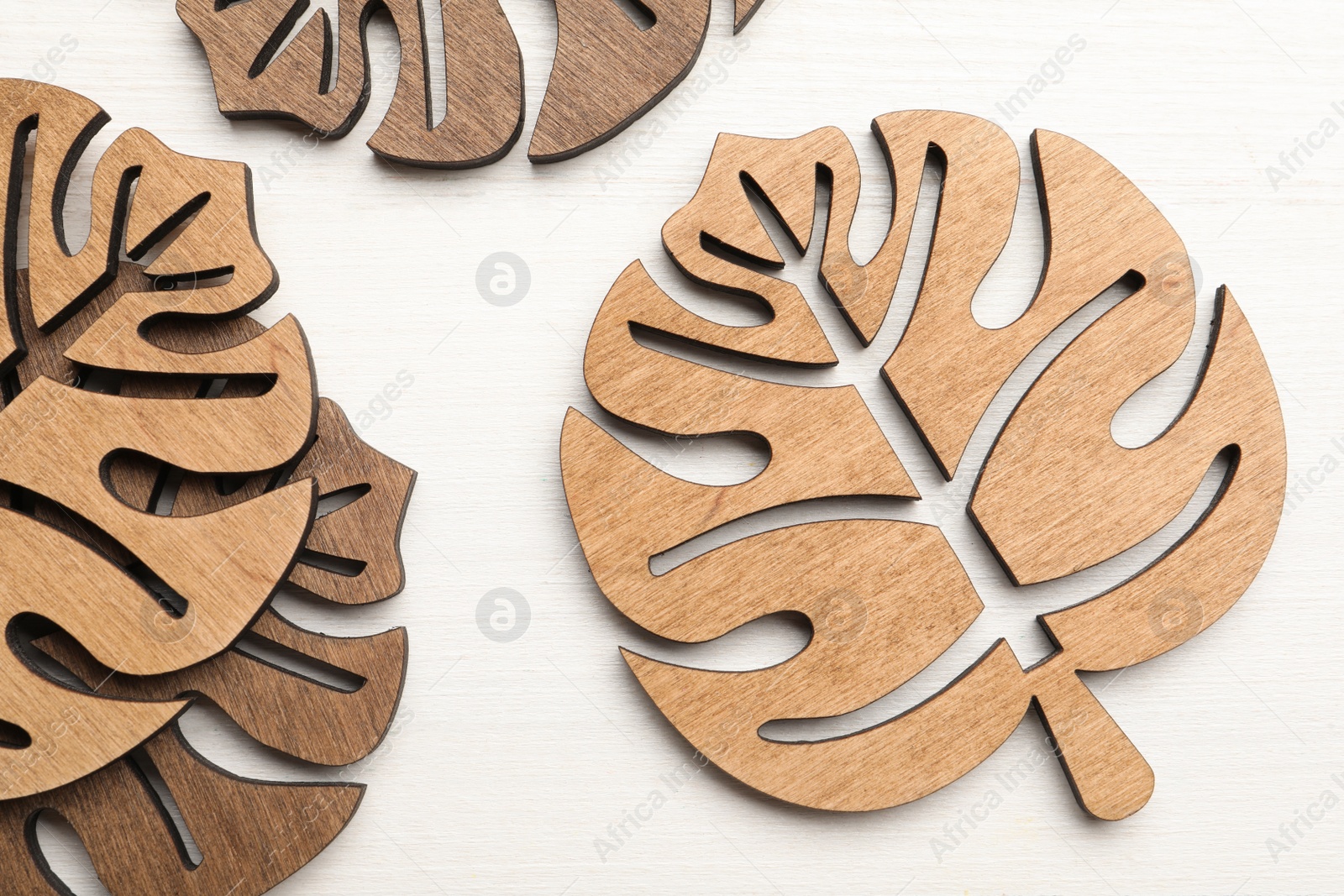 Photo of Leaf shaped wooden cup coasters on white table, flat lay