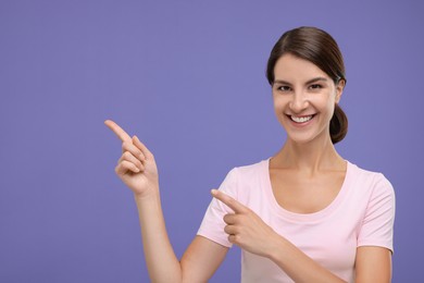 Photo of Special promotion. Happy woman pointing at something on violet background, space for text