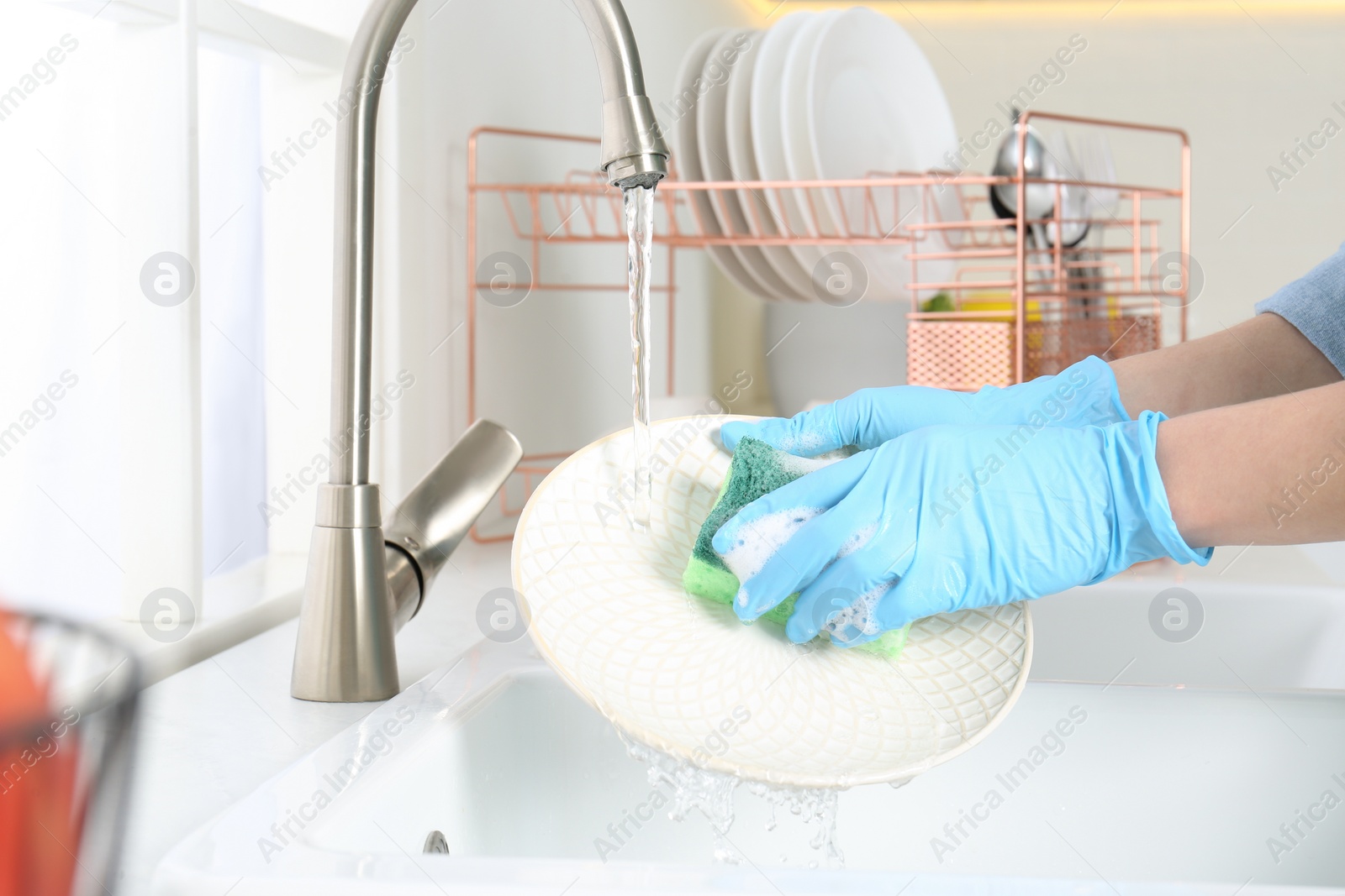 Photo of Woman washing plate in modern kitchen, closeup