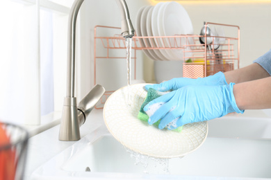 Photo of Woman washing plate in modern kitchen, closeup