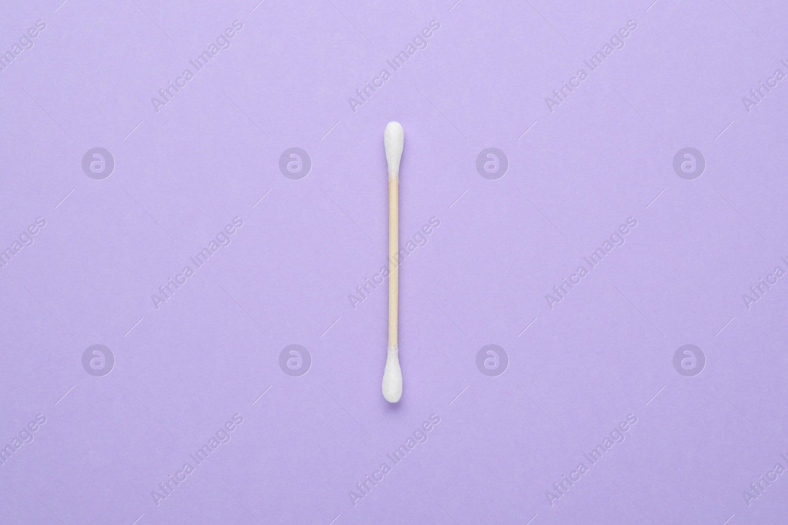 Photo of One wooden cotton bud on violet background, top view