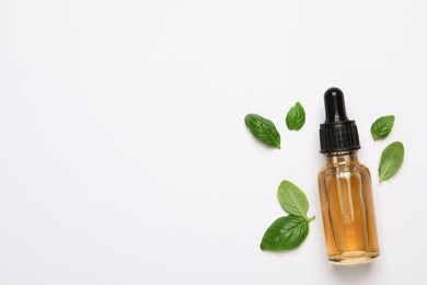 Photo of Bottle of essential basil oil and fresh leaves on white background, flat lay. Space for text