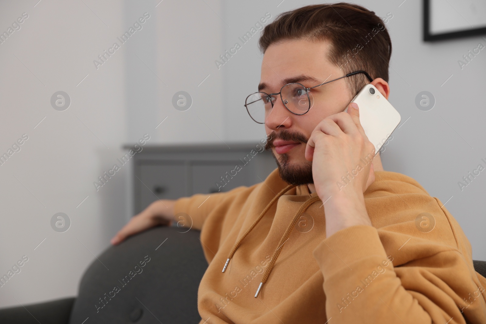 Photo of Man talking on smartphone in room. Space for text