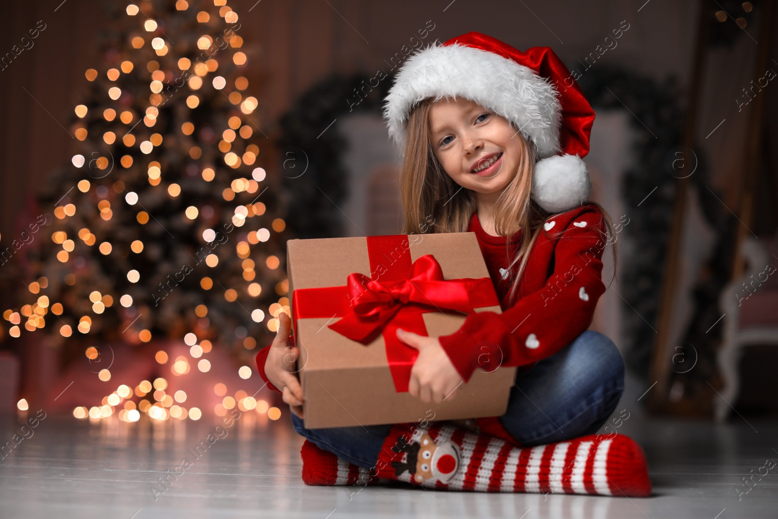 Photo of Cute little child with Christmas gift at home