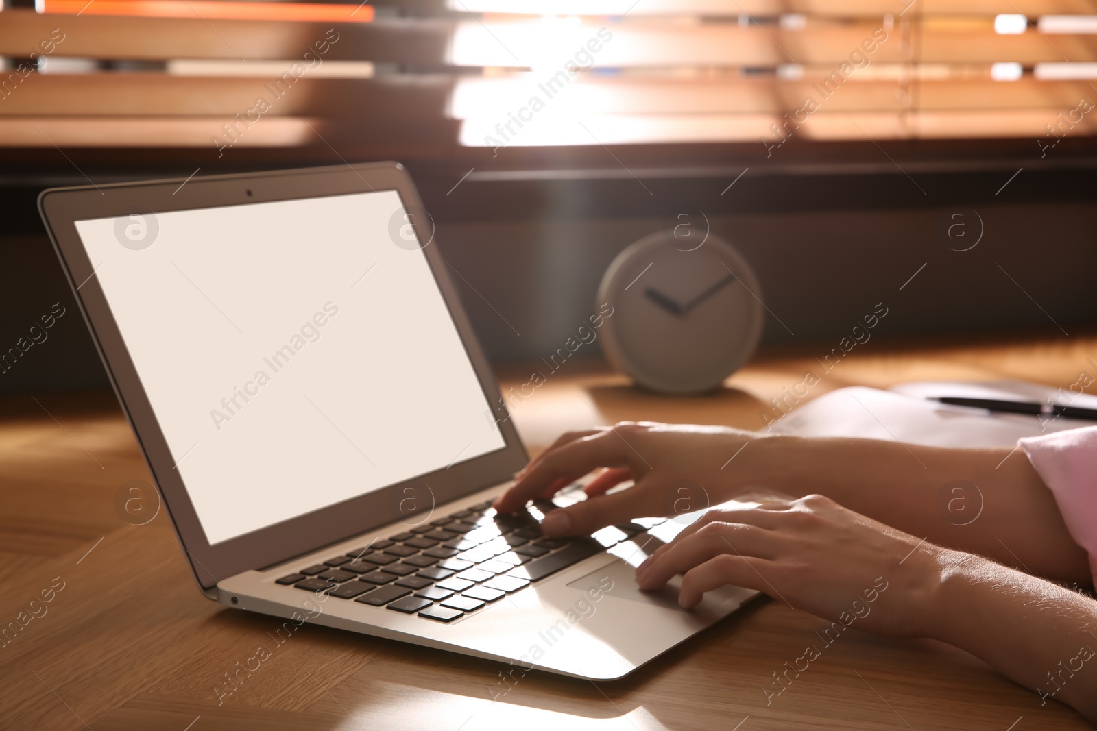 Photo of Woman using modern laptop at wooden table indoors, closeup