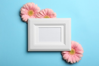 Photo of Empty photo frame and flowers on color background, top view. Space for text