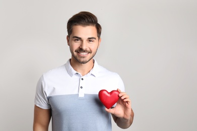 Photo of Portrait of young man with decorative heart on light background. Space for text