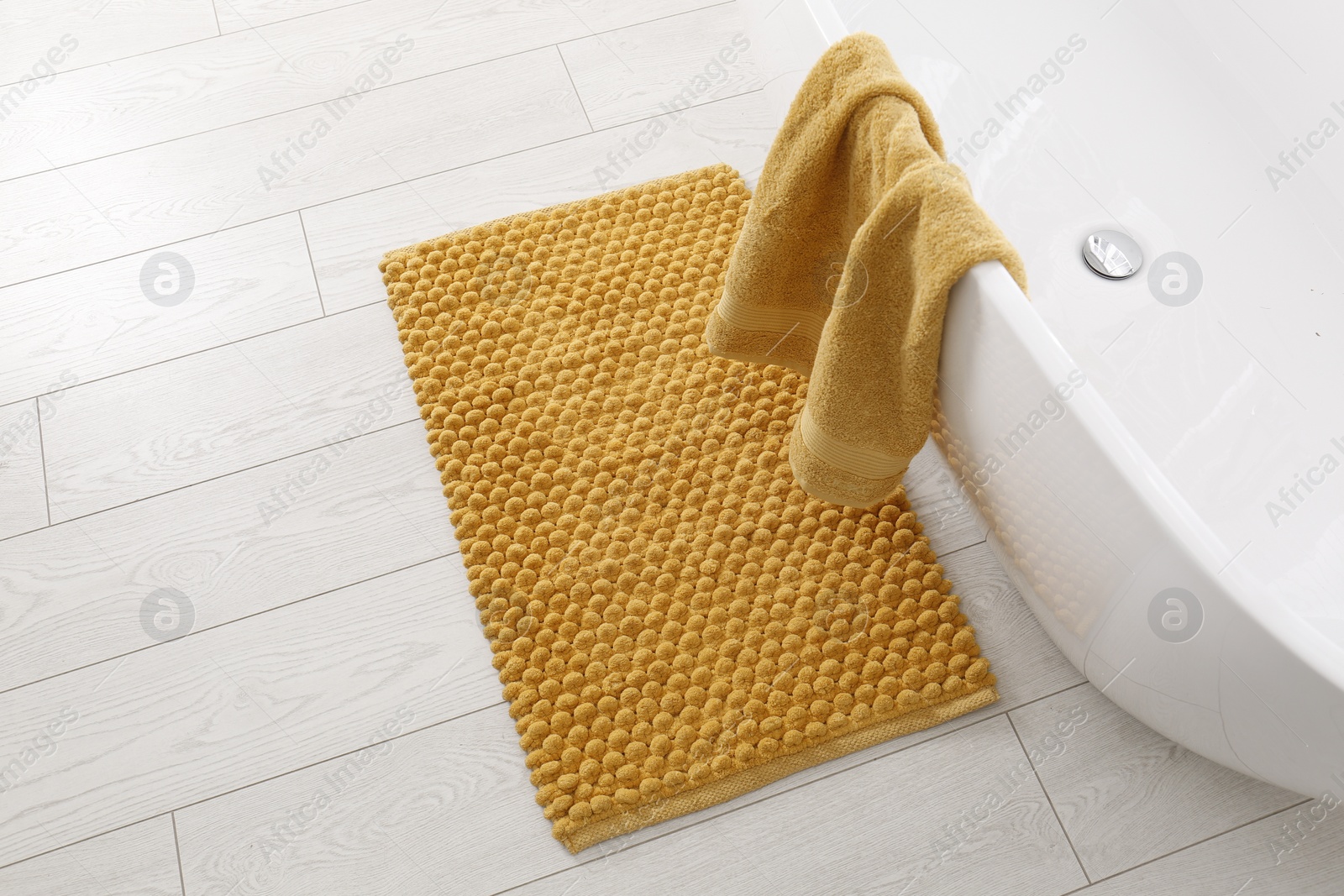 Photo of Soft orange bath mat on floor in bathroom