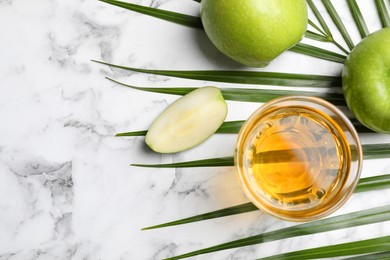 Photo of Fresh juice, apples palm leaf on white marble table, flat lay