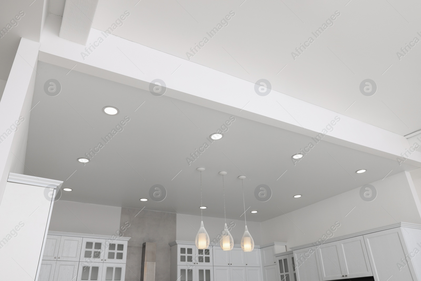 Photo of Ceiling with modern lamps, furniture and cooker hood in stylish kitchen, low angle view