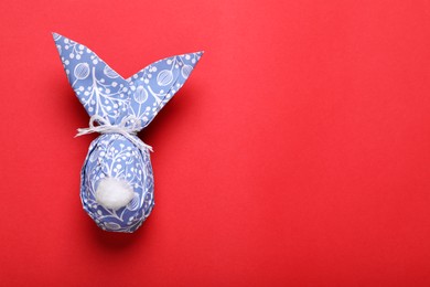 Photo of Easter bunny made of wrapping paper on red background, top view. Space for text