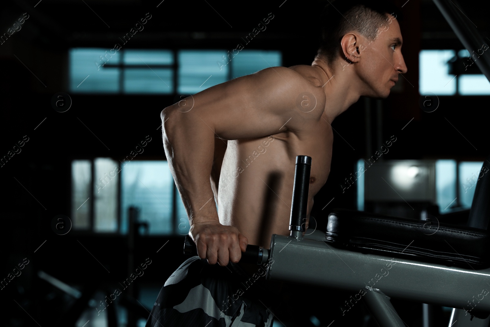 Photo of Strong man working out on parallel bars in modern gym