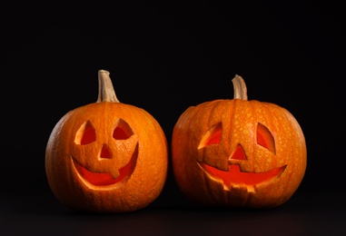 Photo of Pumpkin heads on black background. Jack lantern - traditional Halloween decor
