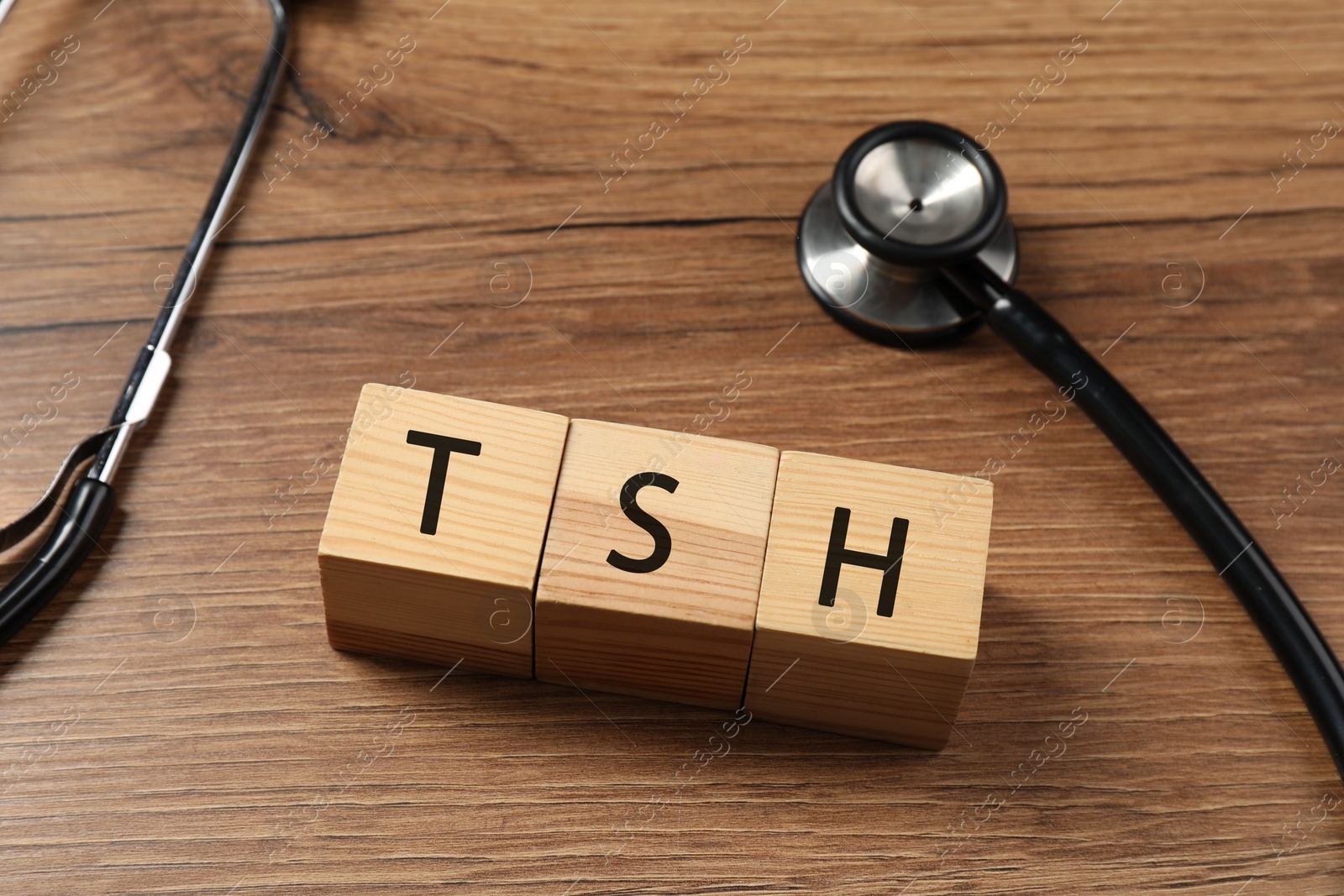 Photo of Endocrinology. Stethoscope and cubes with thyroid hormones on wooden table