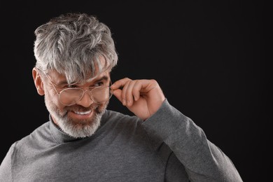 Portrait of smiling man with beautiful hairstyle on black background. Space for text