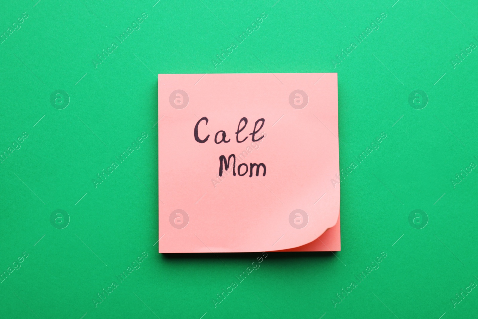 Photo of Paper note with words Call mom on green background, top view