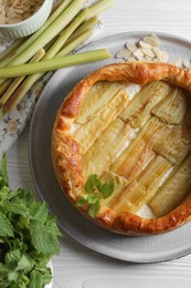 Photo of Freshly baked rhubarb pie and stalks on white wooden table, flat lay