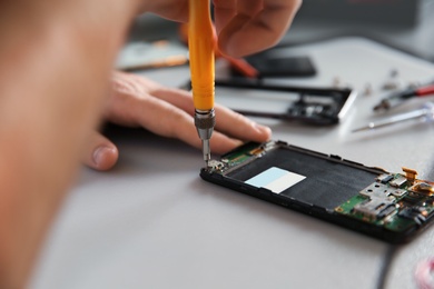 Photo of Technician repairing mobile phone at table, closeup