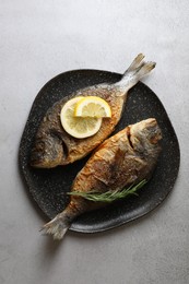Delicious dorado fish with rosemary and lemon on light grey table, top view