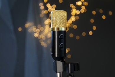 Photo of Microphone against dark grey background with blurred lights. Sound recording and reinforcement