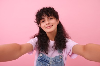 Beautiful woman taking selfie on pink background