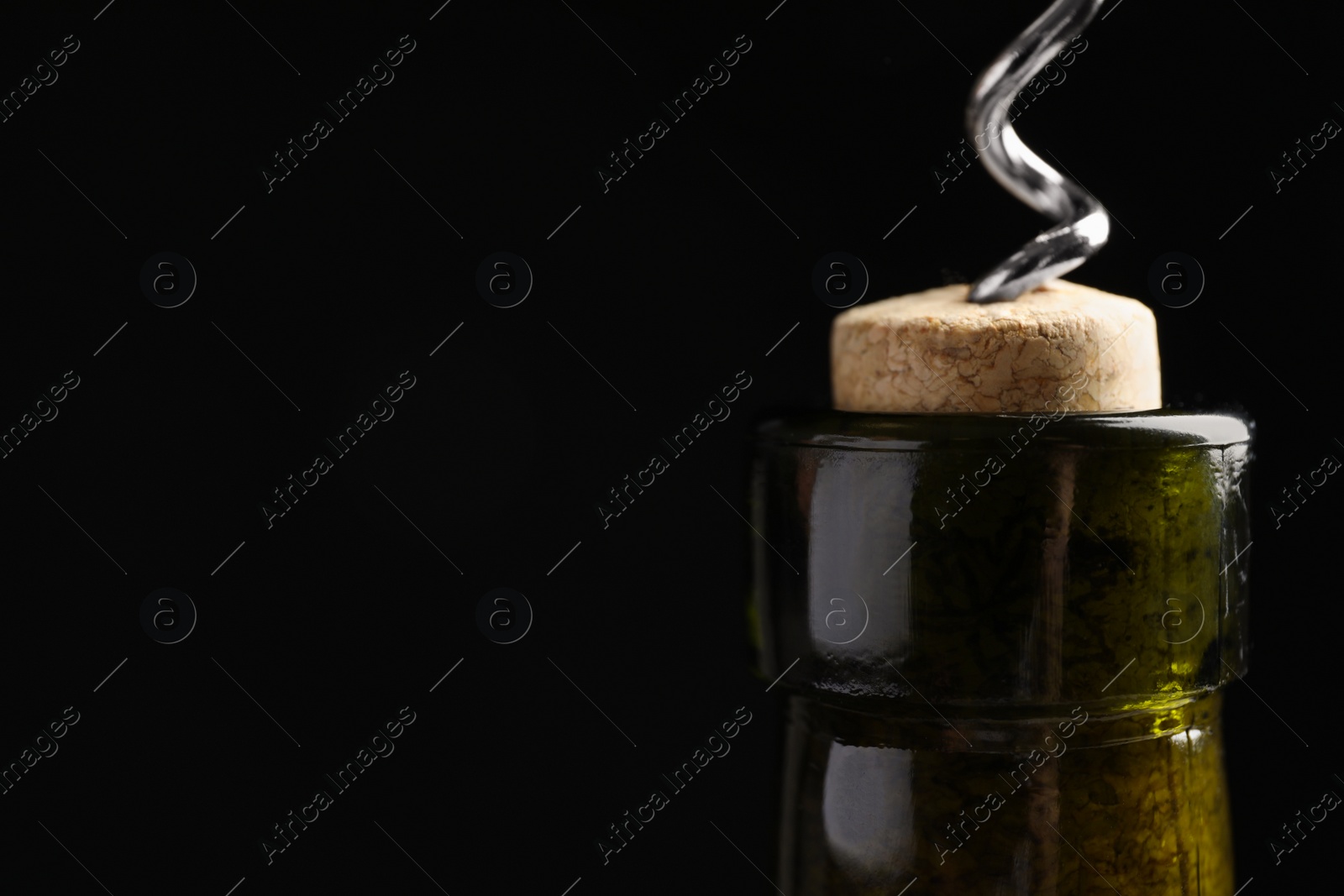 Photo of Opening wine bottle with corkscrew on black background, closeup. Space for text
